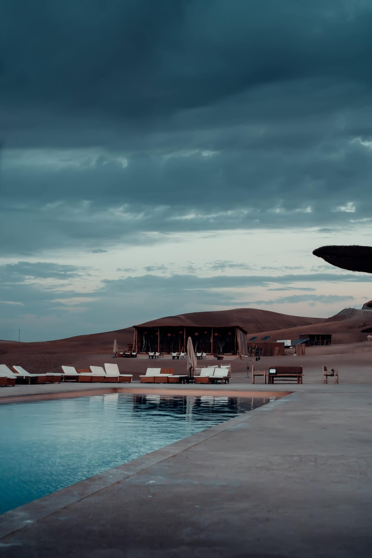 Tranquil desert scene with a luxury poolside view at a glamping resort in Agafay, Morocco.